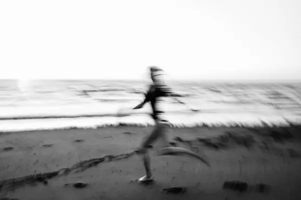 Une silhouette qui court sur une plage, floue de mouvement
