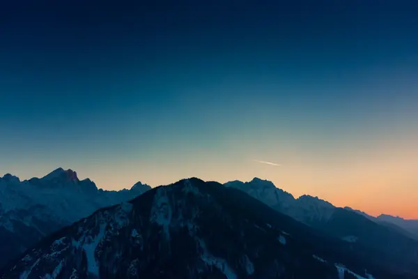 Des montagnes enneigées sous un ciel de crépuscule